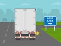 Truck is about to to turn right on highway. Heavy vehicle driving on motorways. Rest area road or traffic sign. Back view. Royalty Free Stock Photo