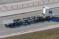 Truck with a trailer and an empty long platform rides in the city on the highway