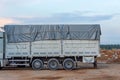 Truck with a white body with sides covered with a gray tarpaulin rain protection