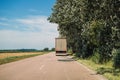 Trucking and freight transportation, rear view of large semi-truck driving along the road through countryside landscape in summer