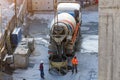 Trucks with a concrete mixer unloads concrete cement into a container suspended on the cables of a construction crane, workers