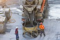 Trucks with a concrete mixer unloads concrete cement into a container suspended on the cables of a construction crane, workers