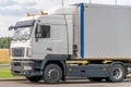 Trucks with containers in the parking lot along the highway against the background of clouds. The concept of logistics, transport Royalty Free Stock Photo