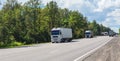 Trucks deliver cargo in opposite directions on a suburban highway