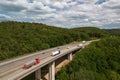 trucks are driving on a freeway through a forest filled valley