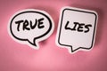 True and Lies concept. White speech bubbles with text on a pink background Royalty Free Stock Photo