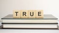 True - word written on wooden blocks. text is written in black letters and is reflected in the mirror surface of the table, blue Royalty Free Stock Photo