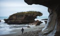 Truman Track, New Zealand,  October 8, 2019: Beautiful image of blonde European girl walking on a beach with a rock formation in Royalty Free Stock Photo