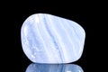 Trumbled blue chalcedony mineral stone in front of black background