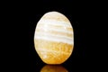 Trumbled honey calcite mineral stone in front of black background