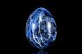 Trumbled sodalite mineral stone in front of black background