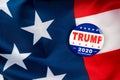 Trump presidential election campaign 2020 vote button; pin laying on the american flag.trump presidential election campaign 2020 v