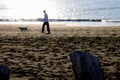 Trunks and young man and his dog silhouettes walking on the beach, in the foreground, wintertime afternoon