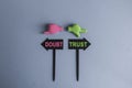 Trust or doubt symbol. Concept word trust or doubt on beautiful signpost with two arrows. Beautiful grey background. Toy hands are