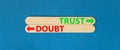 Trust or doubt symbol. Concept word Trust or Doubt on beautiful wooden stick. Beautiful blue table blue background. Business and