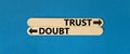 Trust or doubt symbol. Concept word Trust or Doubt on beautiful wooden stick. Beautiful blue table blue background. Business and