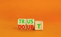 Trust or doubt symbol. Turned wooden cubes and changed the word doubt to trust or vice versa. Beautiful orange table background,