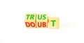 Trust or doubt symbol. Turned wooden cubes and changed the word doubt to trust or vice versa. Beautiful white table, white