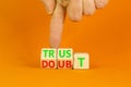 Trust or doubt symbol. Turned wooden cubes and changed the word doubt to trust or vice versa. Beautiful orange table background,