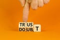 Trust or doubt symbol. Turned wooden cubes and changed the word doubt to trust or vice versa. Beautiful orange table background,