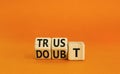 Trust or doubt symbol. Turned wooden cubes and changed the word doubt to trust or vice versa. Beautiful orange table background,
