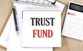 TRUST FUND is written in white notepad near a calculator, clipboard and pen. Business concept Royalty Free Stock Photo