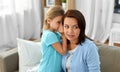 Daughter whispering secret to mother at home