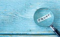 Trust handwritten word with a magnifying glass on blue wooden background