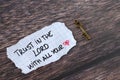 Trust in the LORD with all your heart, inspiring biblical quote written on paper, and ancient key on wooden table