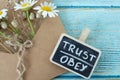 Trust and obey, handwritten words with flowers on vintage wood table