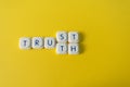 Trust or truth message, made with letter game blocks in a yellow background. Confidence in media concept Royalty Free Stock Photo