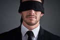 Trust the unseen. Studio shot of a young businessman wearing a blindfold against a gray background.