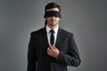 Trust the unseen. Studio shot of a young businessman wearing a blindfold against a gray background.