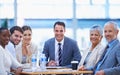 Trust us, were business experts. A portrait of a team of happy businesspeople sitting together at a meeting.