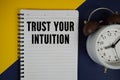 Trust Your Intuition text written on notepad with alarm clock on yellow background Royalty Free Stock Photo