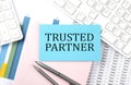TRUSTED PARTNER text on blue sticker on chart with calculator and keyboard,Business concept
