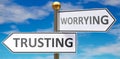 Trusting and worrying as different choices in life - pictured as words Trusting, worrying on road signs pointing at opposite ways