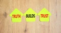 Truth builds trust symbol. Concept words Truth builds trust on green paper houses on a beautiful wooden table wooden background.