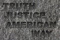 Truth Justice American Way etched in bold, dark gray text on black granite
