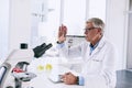 The truth lies in the evidence. a mature scientist analyzing a test tube in a lab.