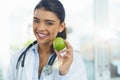 Try to include one of these a day to your diet. Portrait of a young female doctor holding an apple. Royalty Free Stock Photo