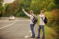 Try to stop some car. Reason people pick up hitchhikers. Missed their bus. Need help. Cheap transport. Transport problem Royalty Free Stock Photo