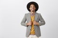 Trying new style, purchasing trendy jacket in store. Portrait of happy successful dark-skinned bearded man in black hat Royalty Free Stock Photo