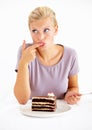 Trying a small taste.... Young woman tasting the frosting of a delicious piece of chocolate cake. Royalty Free Stock Photo