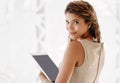 Trying to get my company secrets. Cropped portrait of an attractive young businesswoman using her tablet while standing Royalty Free Stock Photo