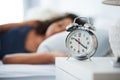 Trying to sleep but this little device wont let me. an attractive young woman laying in bed with an alarm clock on her Royalty Free Stock Photo