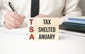 TSA, tax sheltered annuary symbol. Concept words TSA, tax sheltered annuary on wooden blocks. Beautiful white background,