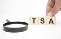 tsa text wooden cube blocks and hand holding magnifying glass on table background Royalty Free Stock Photo