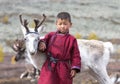 Tsaatan boy, dressed in a traditional deel with a reindeer in a