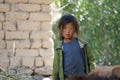 A little girl with look of sorrowof, Tibetan nationality with a sunburn on her face is standing on the street